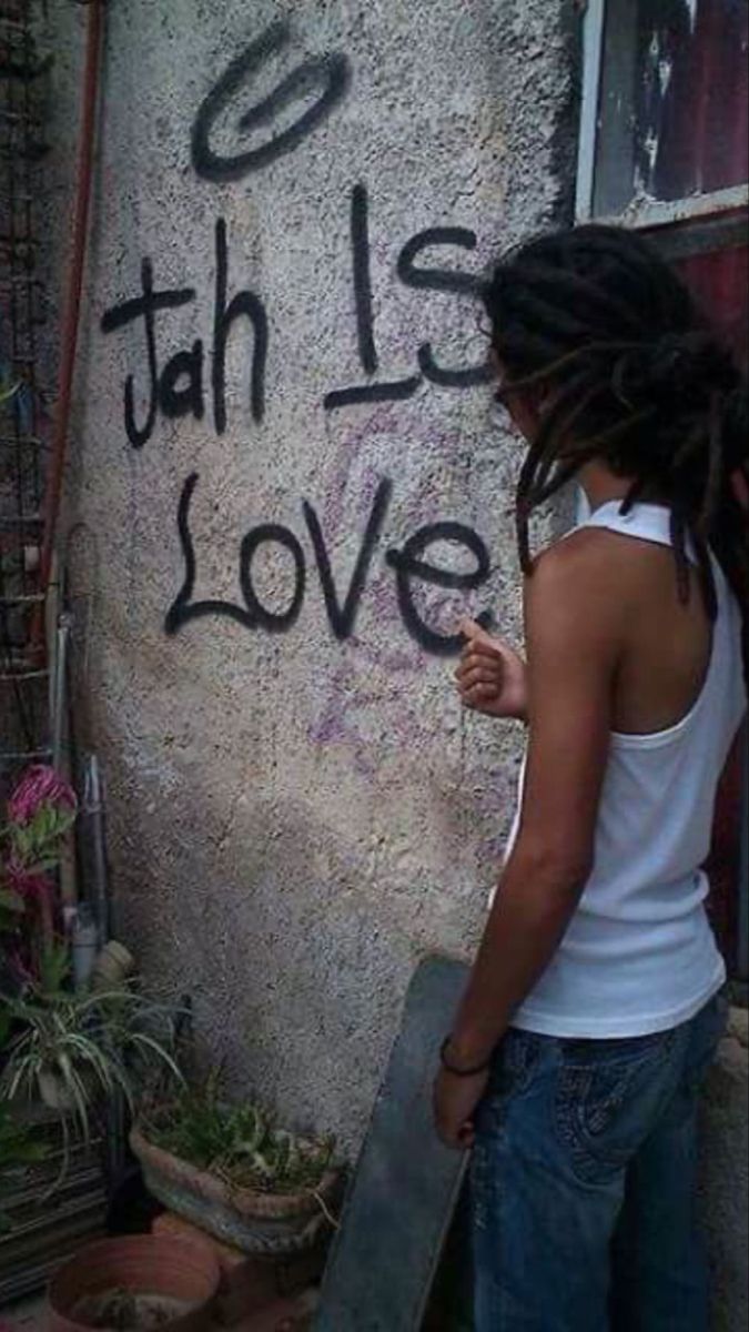 a woman standing next to a wall with graffiti on it