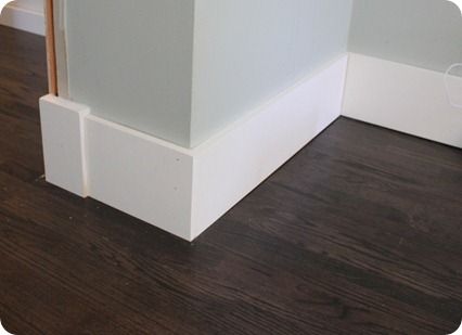 the corner of a room with white walls and wood flooring on top of it