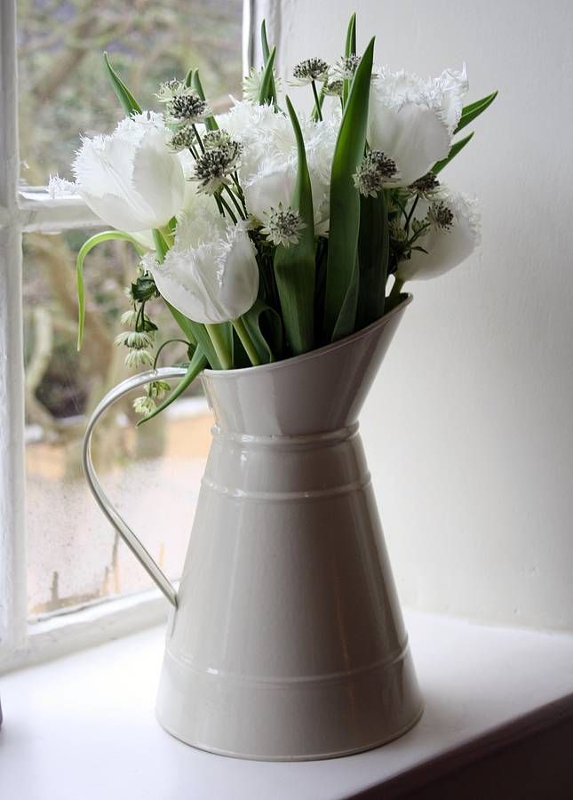 a white vase filled with flowers on top of a window sill