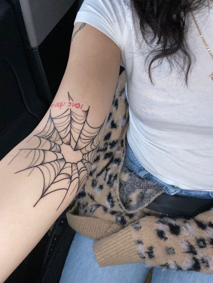 a woman with a spider web tattoo on her arm