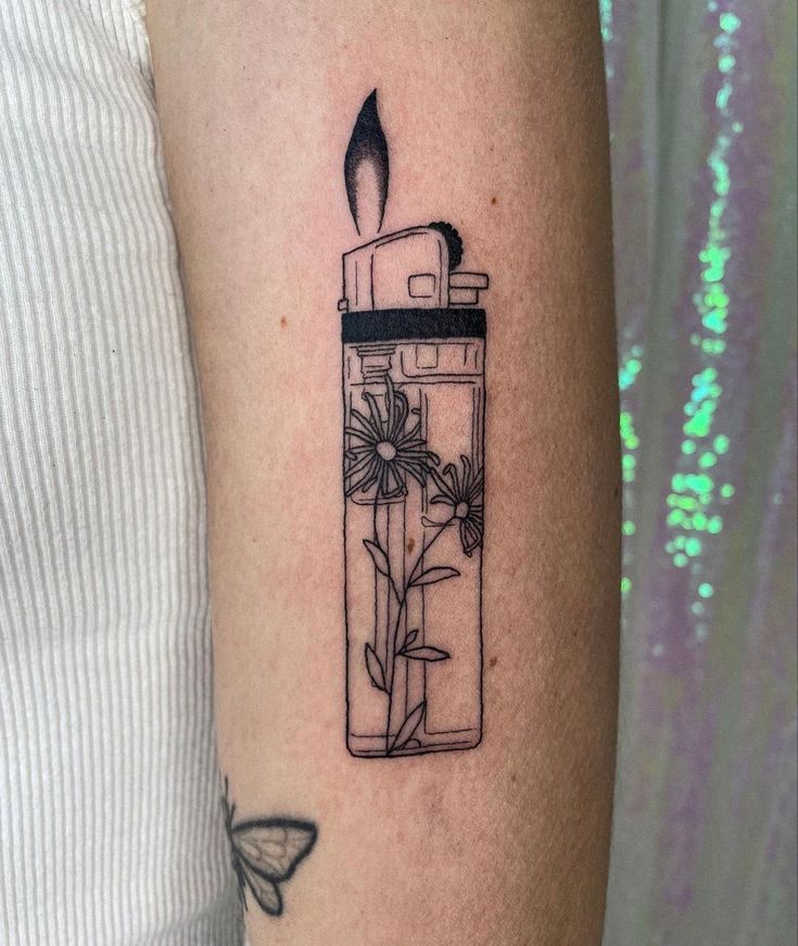 a woman's arm with a tattoo that has a candle in it and flowers inside