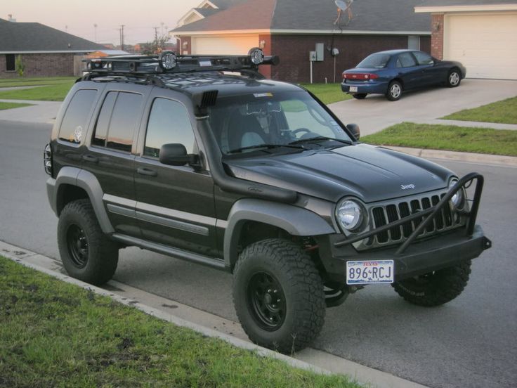 a black jeep is parked on the side of the road in front of a house