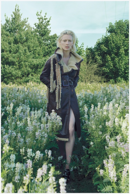 a woman is standing in a field with flowers