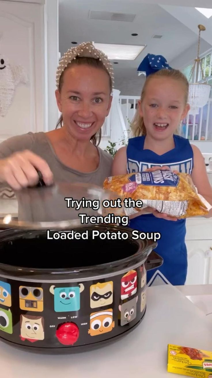 a woman and girl standing in front of a crock pot with food on it