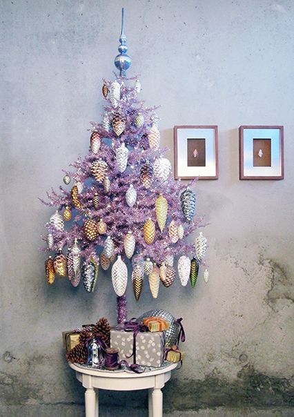 a purple christmas tree sitting on top of a white table next to a gray wall