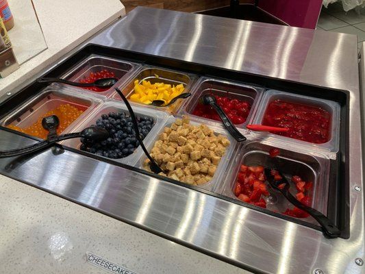 an assortment of fruits and cereals in trays on a counter top at a restaurant