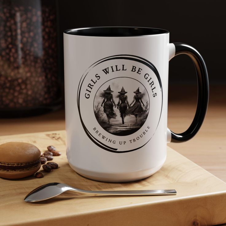 a white and black coffee mug sitting on top of a cutting board next to a spoon