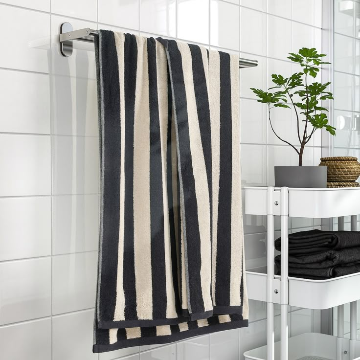 black and white striped towel hanging on the wall next to a shelf with folded towels