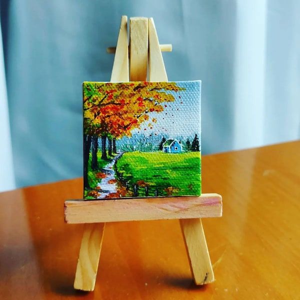 an easel with a painting on it sitting on a table