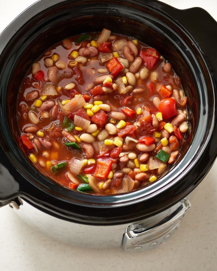 a black crock pot filled with beans and vegetables