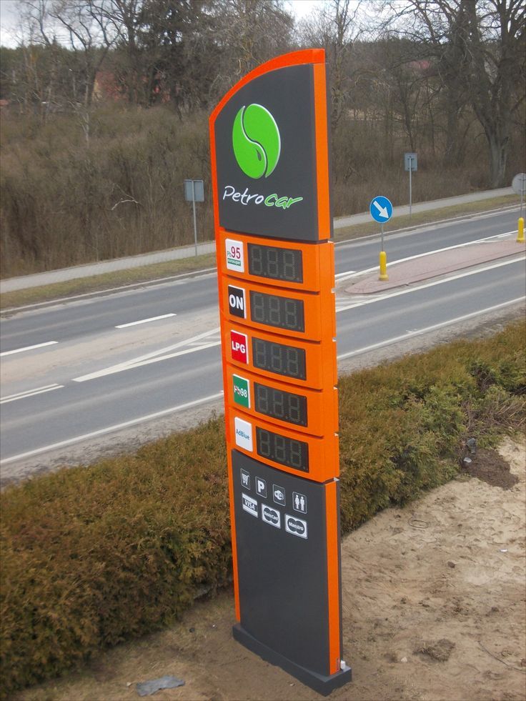 an orange gas pump sitting on the side of a road next to a grass covered field