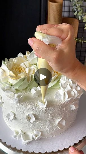 a person is decorating a white cake with flowers