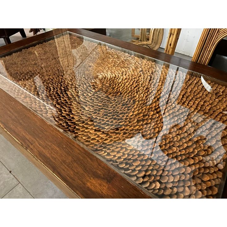 a glass table with lots of brown objects on it's sides and some chairs in the background