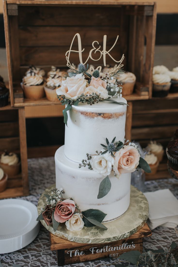 a white wedding cake with flowers on top and the initials ask are placed on it