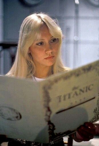 a blonde woman reading a book while sitting at a table