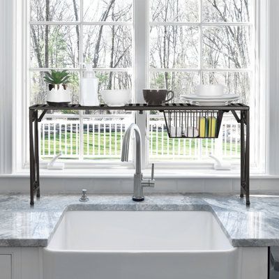 a kitchen sink sitting under a window next to a counter top with dishes on it