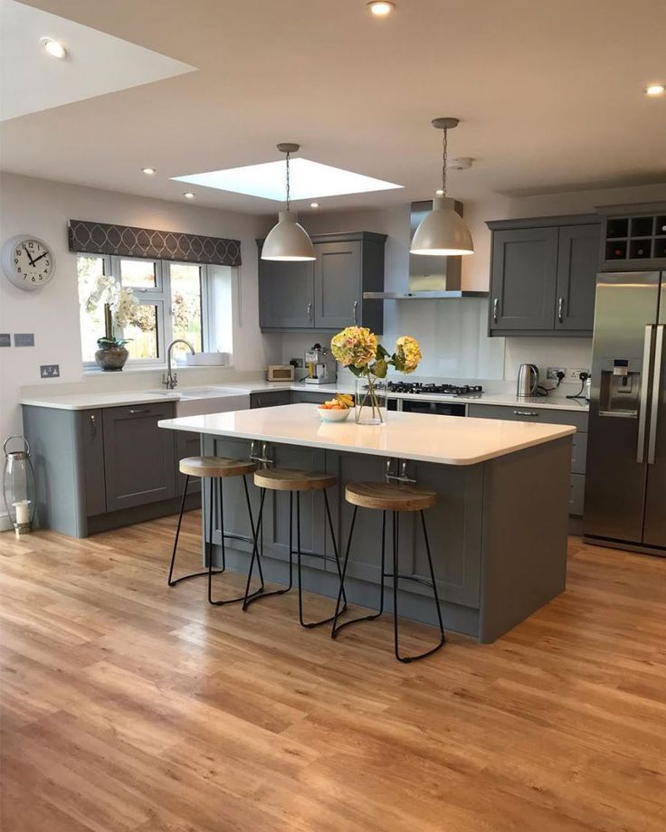 a kitchen with two stools and an island in the middle, surrounded by stainless steel appliances