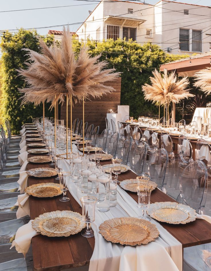 a long table is set up with place settings and centerpieces for an outdoor event