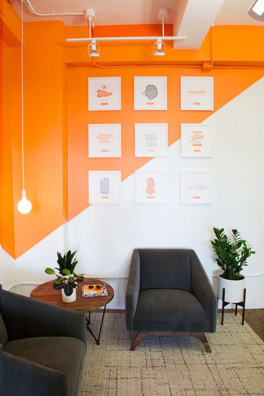 an office with orange and white walls, two chairs and a coffee table in the middle