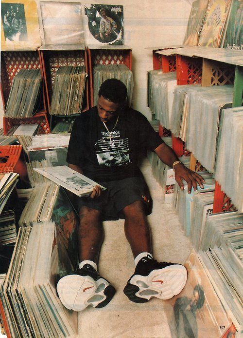 a man sitting on top of a pile of records in a room filled with cds