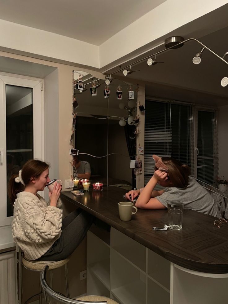 two women sitting at a bar with drinks in front of them and one is eating