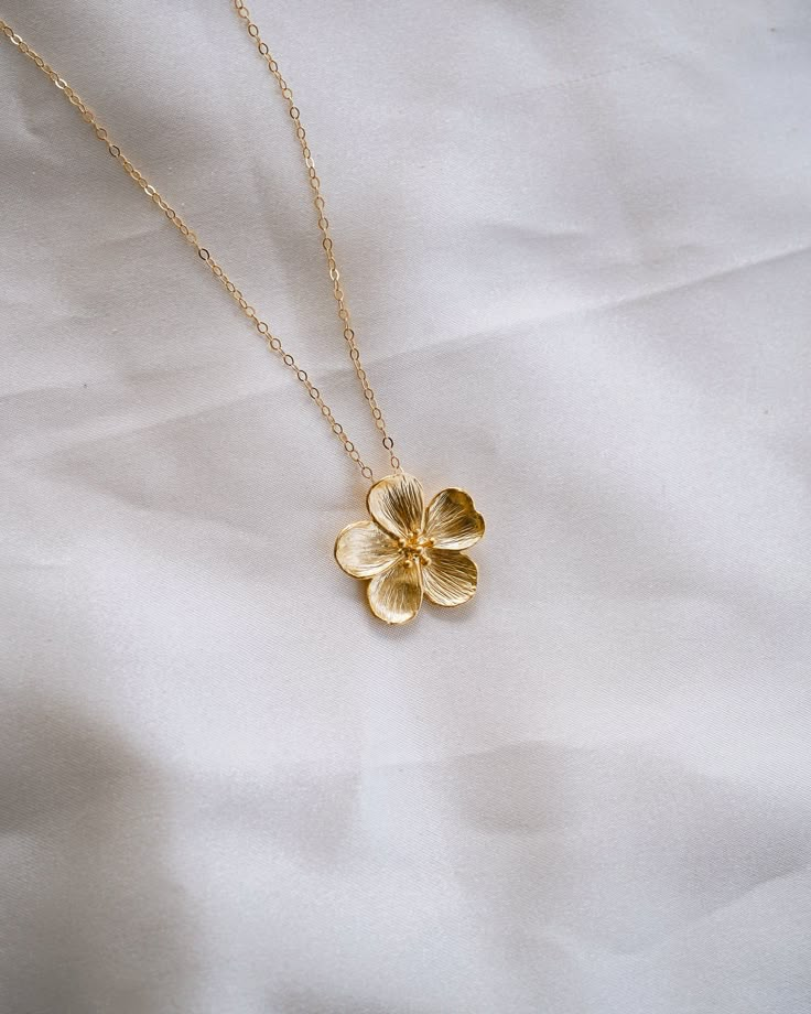 This Bloom Gold Necklace is perfect for letting your beauty blossom! Its golden brilliance sparkles like sunshine, and is sure to turn heads. Add a touch of glamour and make a statement with this gorgeous piece! NECKLACE FEATURES Material: Brass Size: 22.5 x 21.9mm 18K Matte Gold Plated Flower Charm 14K gold filled cable chain & necklace findings Model is wearing 18" length Luxury Gold Flower Necklace, Gold Necklace Flower, Gold Necklaces Aesthetic, Flower Gold Necklace, Golden Necklaces, Gold Flower Necklace, Preppy Jewelry, Pretty Jewelry Necklaces, Beautiful Gold Necklaces