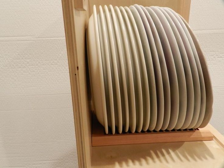 a stack of white plates sitting on top of a wooden shelf