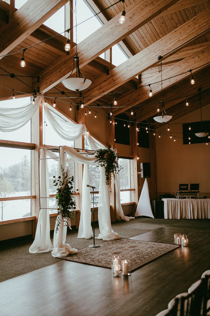 an indoor wedding setup with candles and flowers on the dance floor in front of large windows