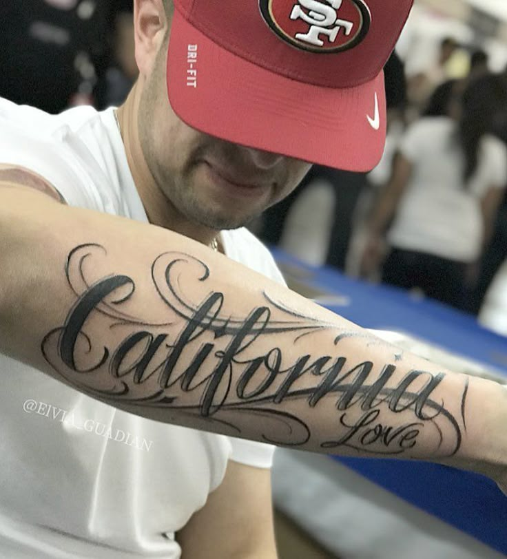 a man with a san francisco giants hat on his arm and the word california in cursive writing