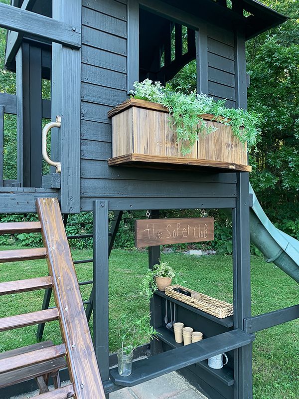 a wooden structure with plants on it and a slide in the back