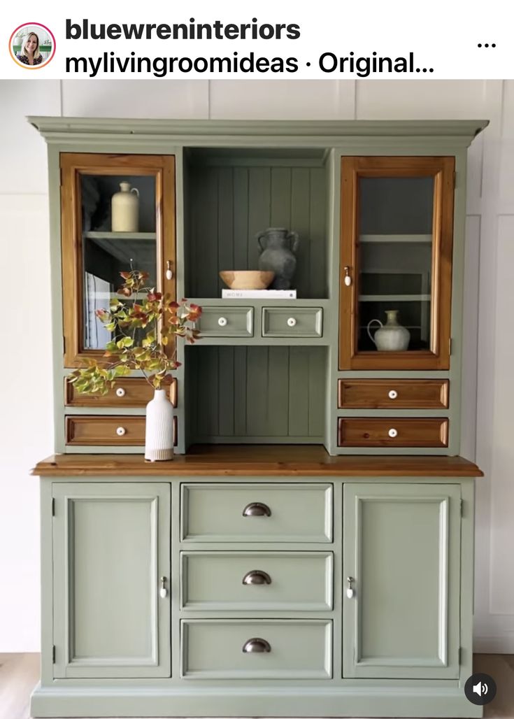 an old china cabinet painted green with wood trim