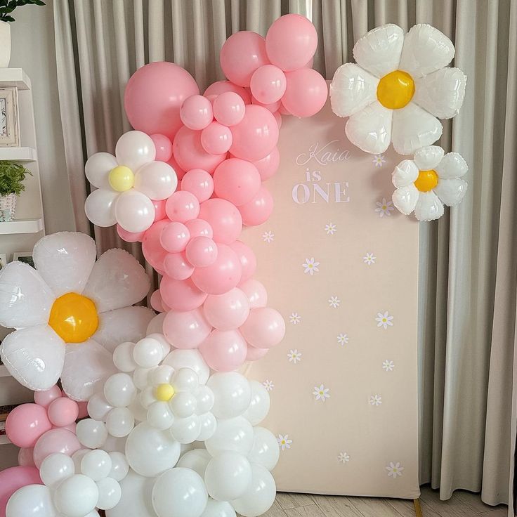 the balloon arch is decorated with daisies and balloons for a baby's first birthday