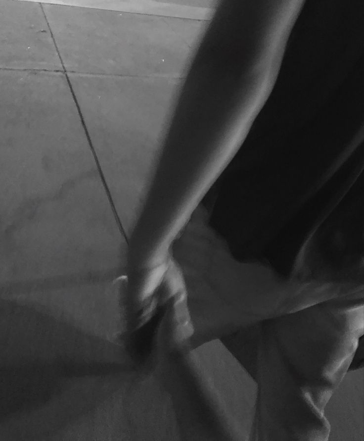 black and white photograph of person holding something in their hand while standing on the ground