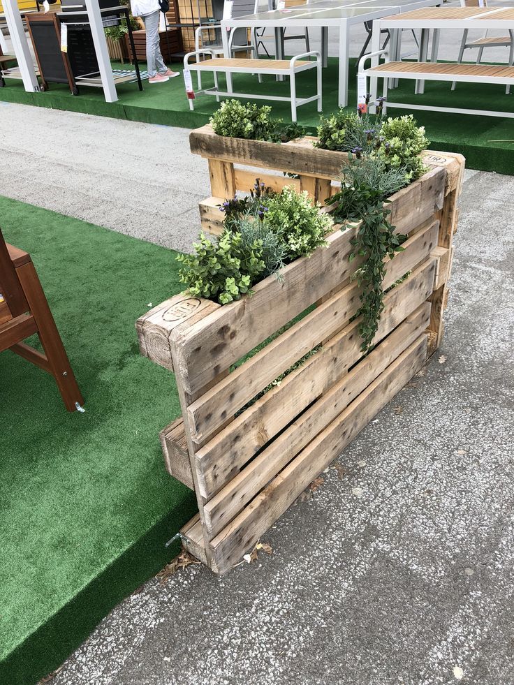 two wooden planters with plants growing out of them on display at an outdoor event