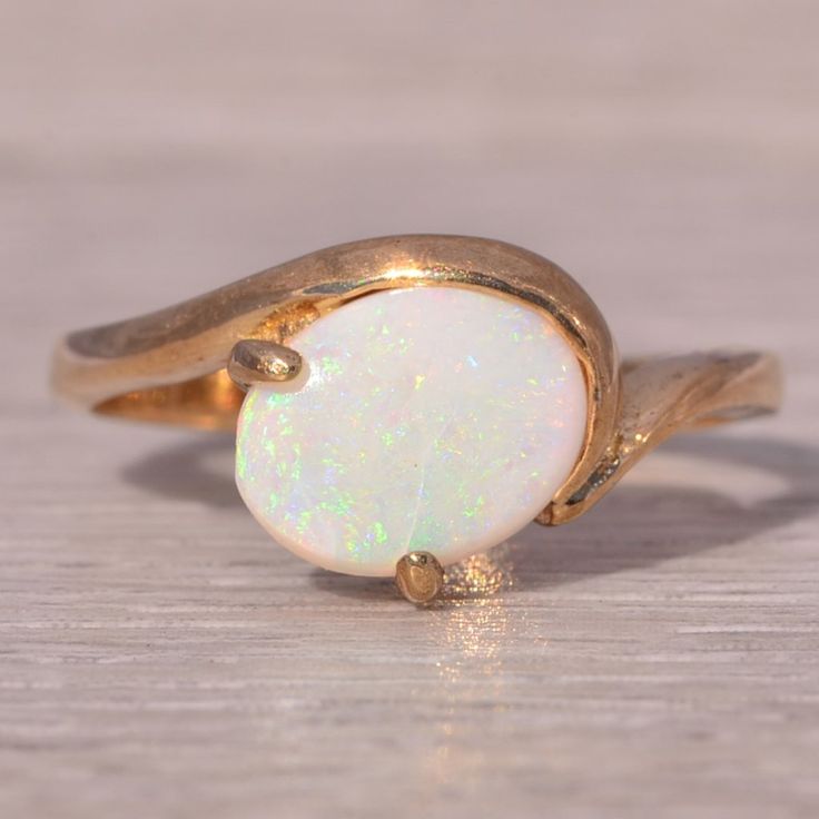 This Stunning Piece, Known As The Australian Beauty, Features A Mesmerizing Australian Opal As Its Centerpiece. The Opal's Captivating Play-Of-Color Displays An Array Of Vibrant Hues, Elegantly Set In A Flowing Yellow Gold Band. The Ring Is Crafted With Italian Craftsmanship, Ensuring Its Quality And Timeless Design. The Ring Is Currently A Finger Size 6.5 Yet Can Be Adjusted To Any Finger Size For An Additional Charge Upon Request, Ensuring A Perfect Fit. Australian Opal Ring, Yellow Gold Color, Beauty Features, Italian Craftsmanship, Opal Ring, Australian Opal, Gold Band, Opal Rings, Womens Jewelry Rings