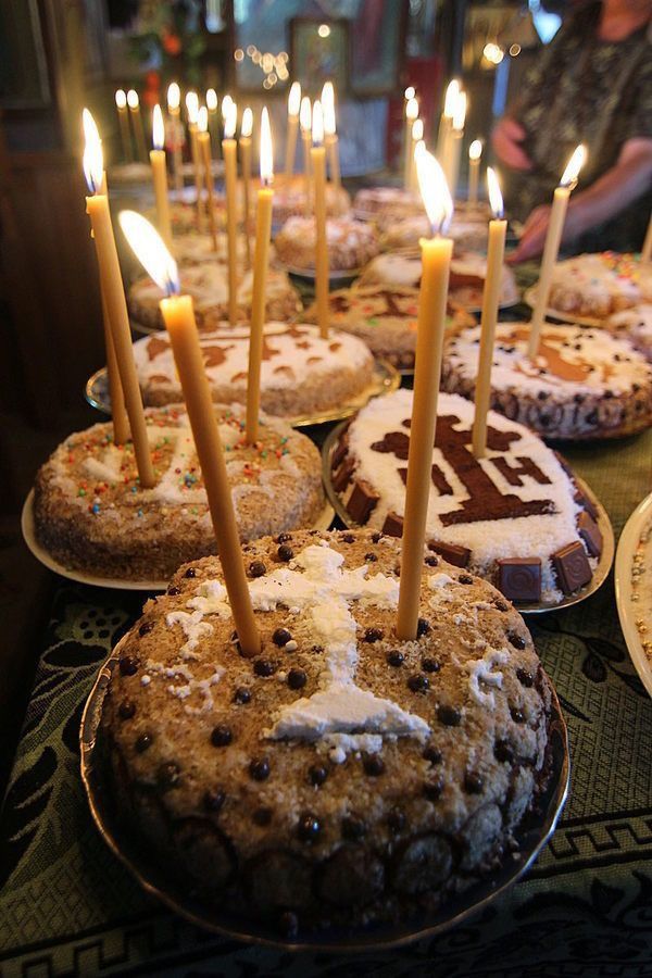 a table topped with lots of cakes covered in frosting and lite up candles