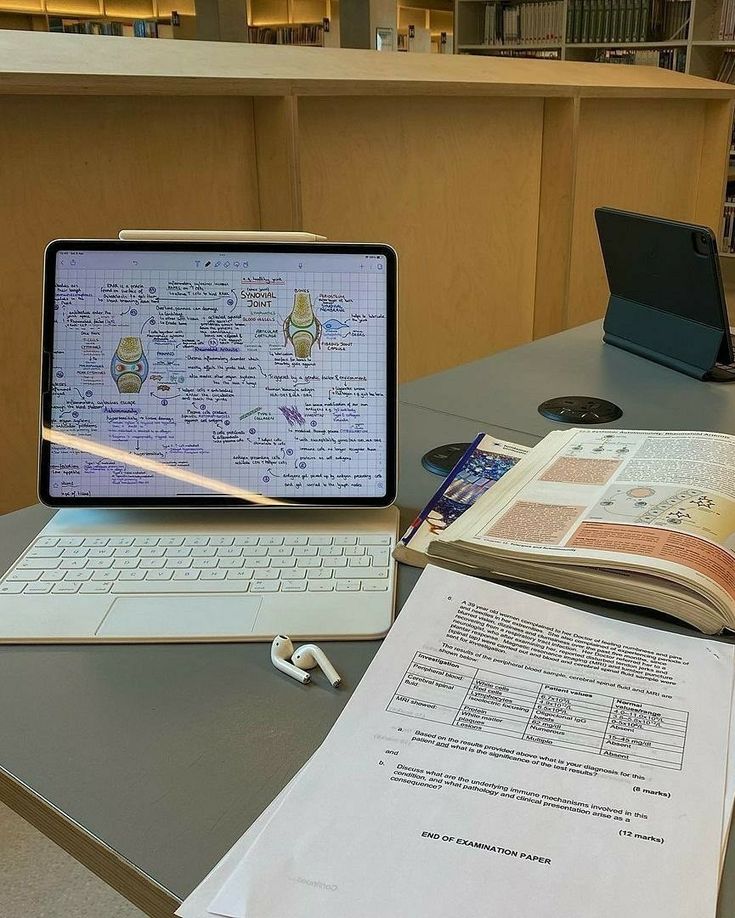 an open laptop computer sitting on top of a desk next to a book and papers