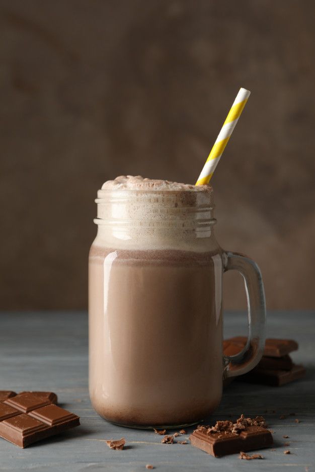 there is a cup with a drink in it and some chocolate on the table next to it