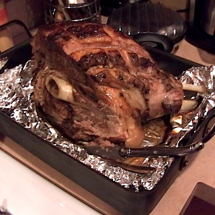 a roasting pan filled with meat and vegetables on top of tin foil covered counter