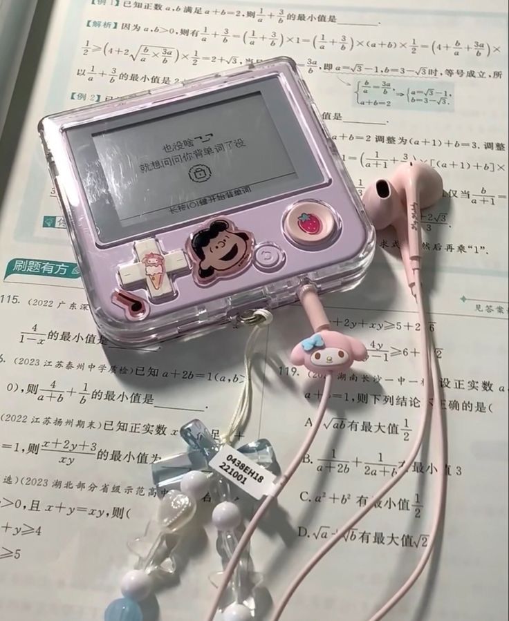 an electronic device with ear buds attached to it sitting on top of some music sheets