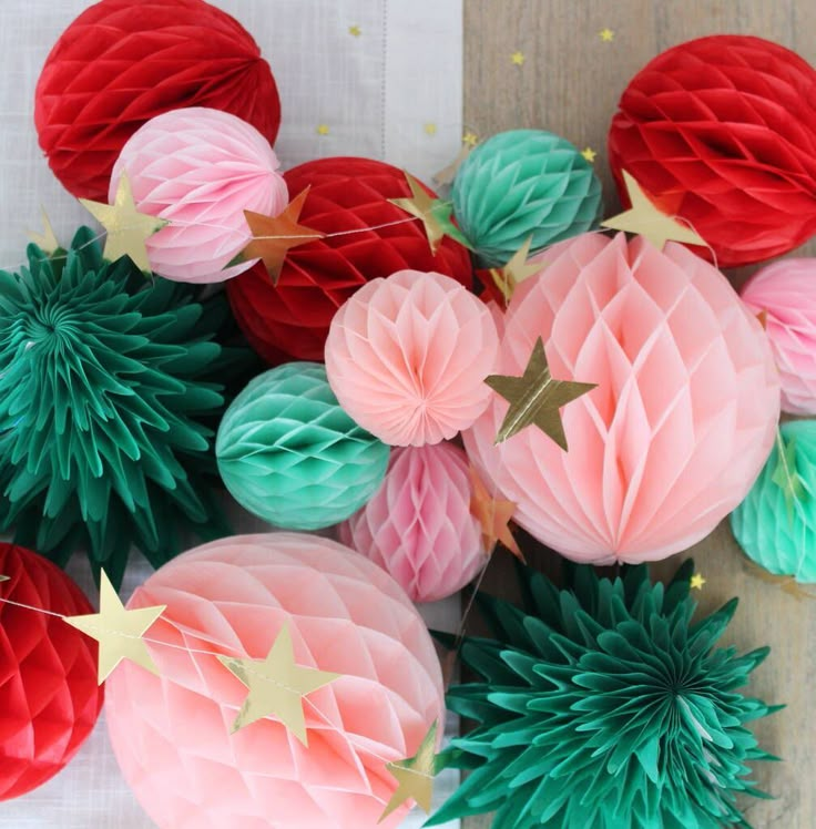 paper balls and stars are arranged on a table top with red, green and pink decorations