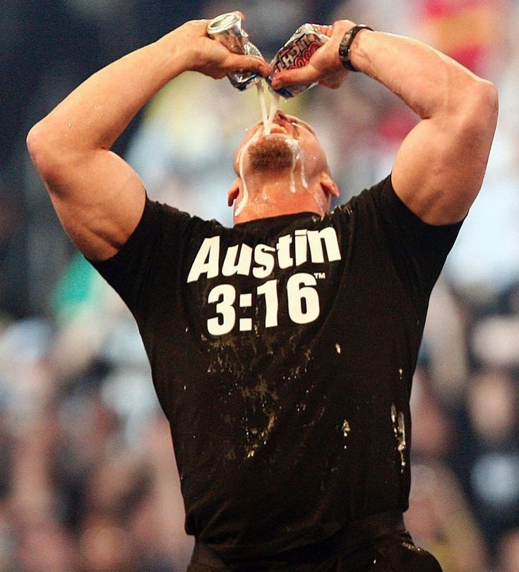 a man drinking water from a bottle while standing in the middle of a crowd with his hands on his head