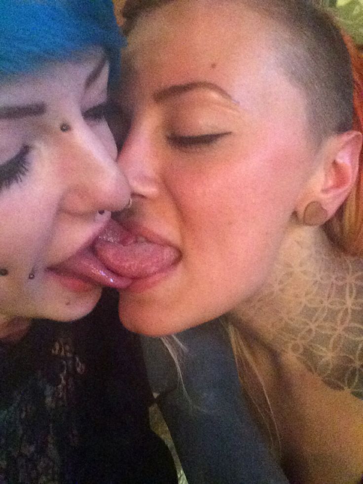 two women are kissing each other with their noses covered in fake eyelashes and piercings