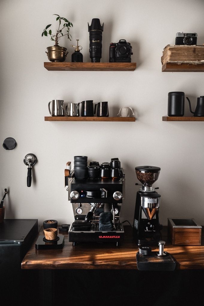 a coffee machine sitting on top of a wooden table next to shelves filled with cups