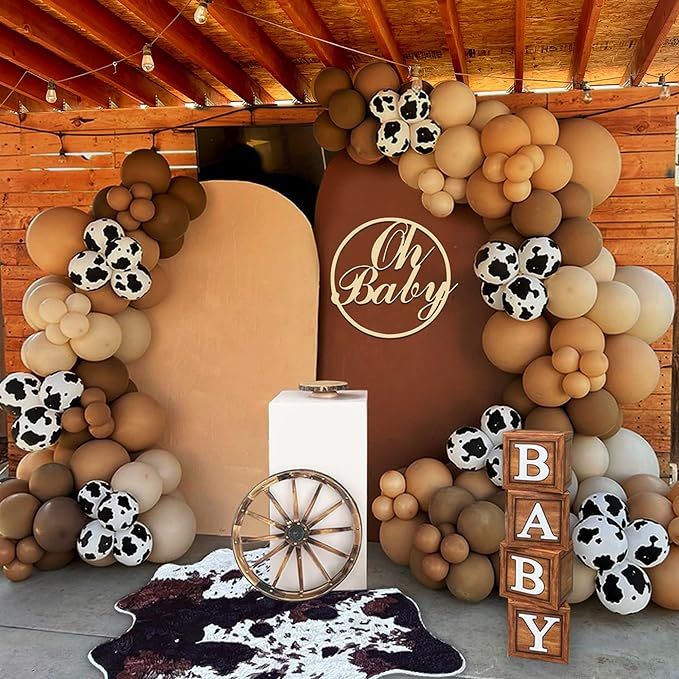 a baby shower is decorated with cow print balloons and an old fashioned wagon for decoration