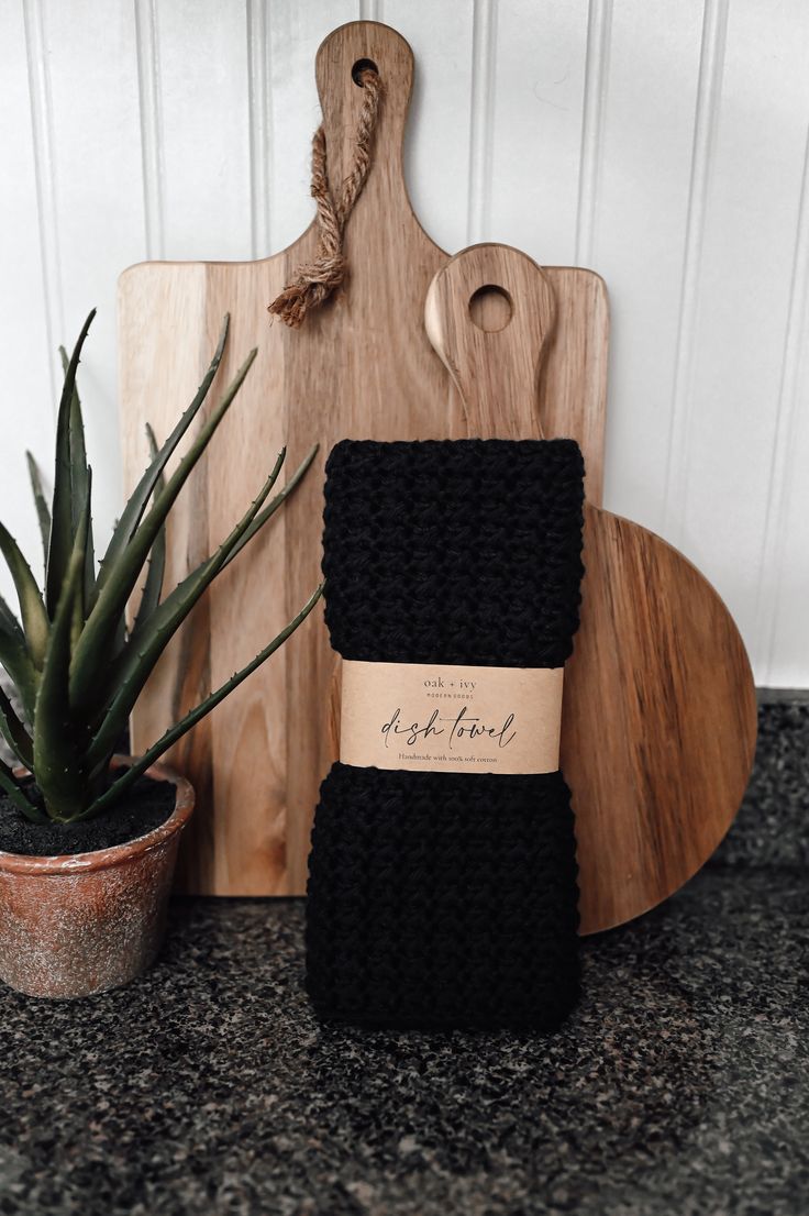 a wooden cutting board sitting on top of a counter next to a potted plant