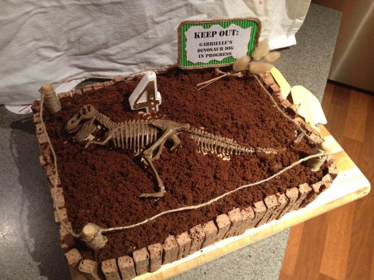 there is a cake made to look like a skeleton in the dirt with a sign on it