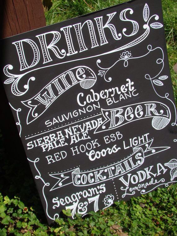 a chalkboard sign advertising drinks in the grass