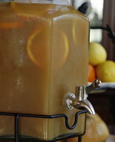 a beverage dispenser filled with liquid sitting on top of a counter next to fruit