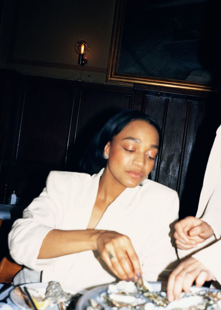 a woman sitting at a table in front of a plate of food with chopsticks